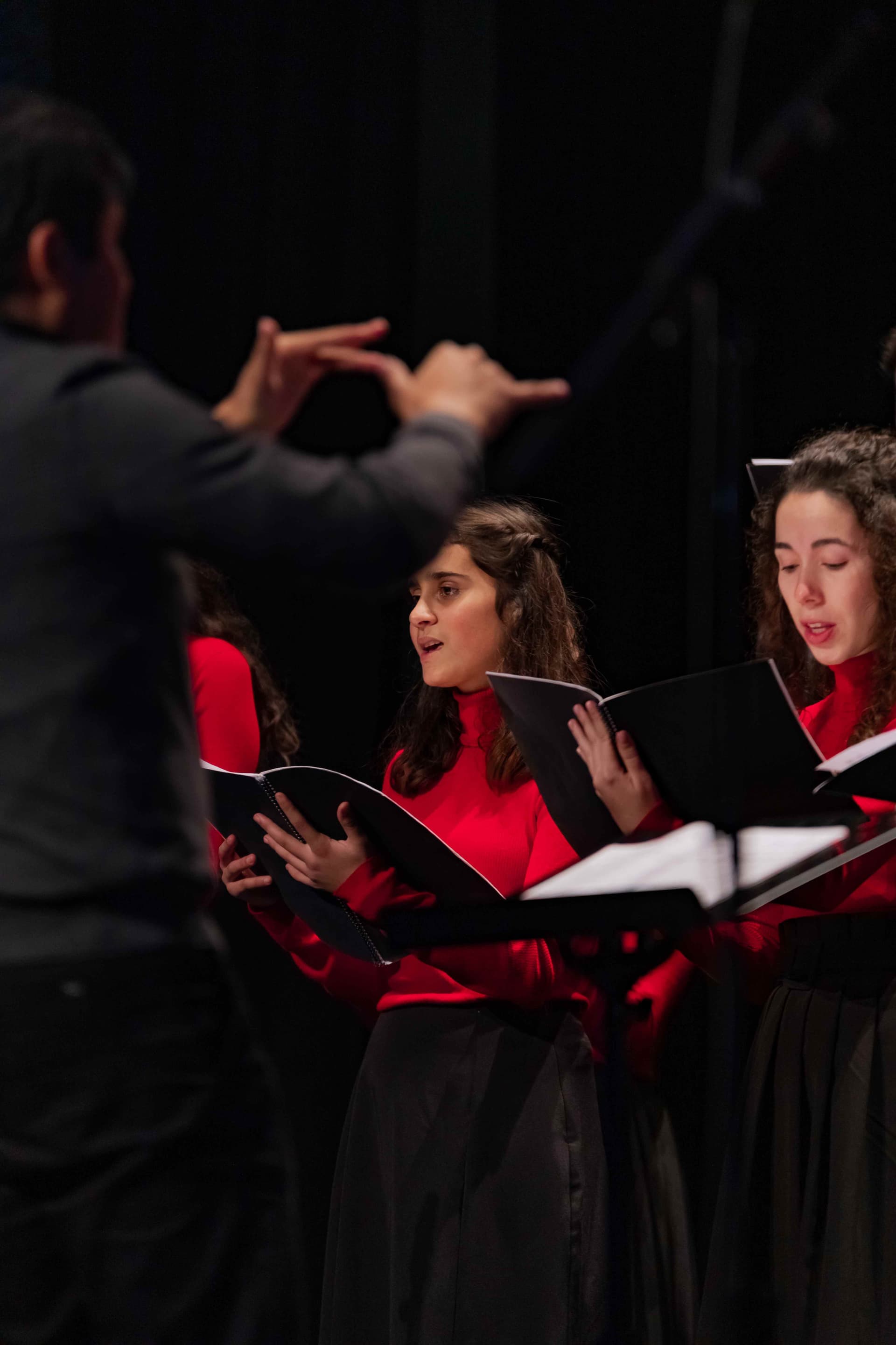 Coralistas a cantar com o regente a dirigir